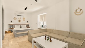 A modern living room with a sectional sofa, a white coffee table, and a large window. - Molino Hotel (Çeşme)