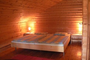 Ein Schlafzimmer einer Holzhütte mit einem Bett, zwei Nachttischen und einem roten Teppich.