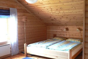 A wooden cabin bedroom with a single bed, a window with a curtain, and a ceiling light fixture. - Holiday home in Lur with swimming pool (Lur)