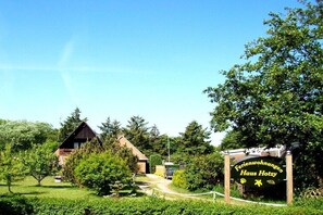 Ländliche Umgebung mit einem Holthaus und einem Schild mit der Aufschrift 'Ferienwohnungen Haus Hotzy'.