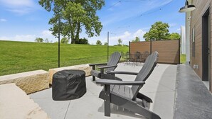 Un patio exterior con sillas tipo Adirondack, una mesa y un área de estar cubierta.