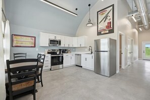 A kitchen with white cabinets, stainless steel appliances, and a dining area with a wooden table and chairs.