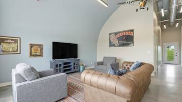 A living room with a flat-screen TV, two sofas, a rug, and a vintage sign on the wall.