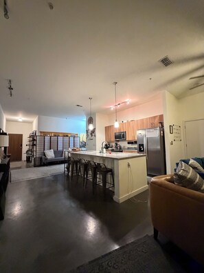 A modern kitchen with a central island, bar stools, and a refrigerator. - Studio Social - Steps from Stadium! & Pet Friendly (Atlanta)