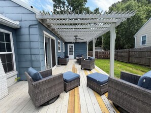 Eine überdachte Terrasse mit Korbmöbeln und einer Pergola.