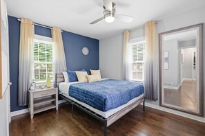 Une chambre à coucher avec un lit, une table de chevet et un ventilateur de plafond.