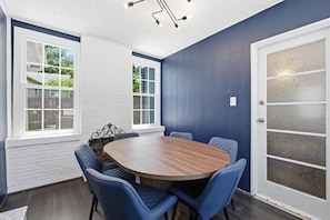 A conference room with a round table, blue chairs, and a white-framed window.