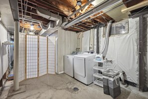 A laundry room with two washing machines, a drying rack, and a utility sink. - Waldo Blue Haven KC Home With Pergola Deck (Kansas City)