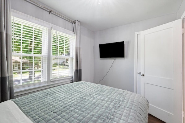 A bedroom with a bed, a TV mounted on the wall, and a door.