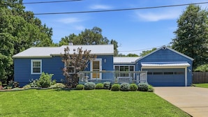A residential house with a blue exterior, a front porch, and a garage. - Waldo Blue Haven KC Home With Pergola Deck (Kansas City)