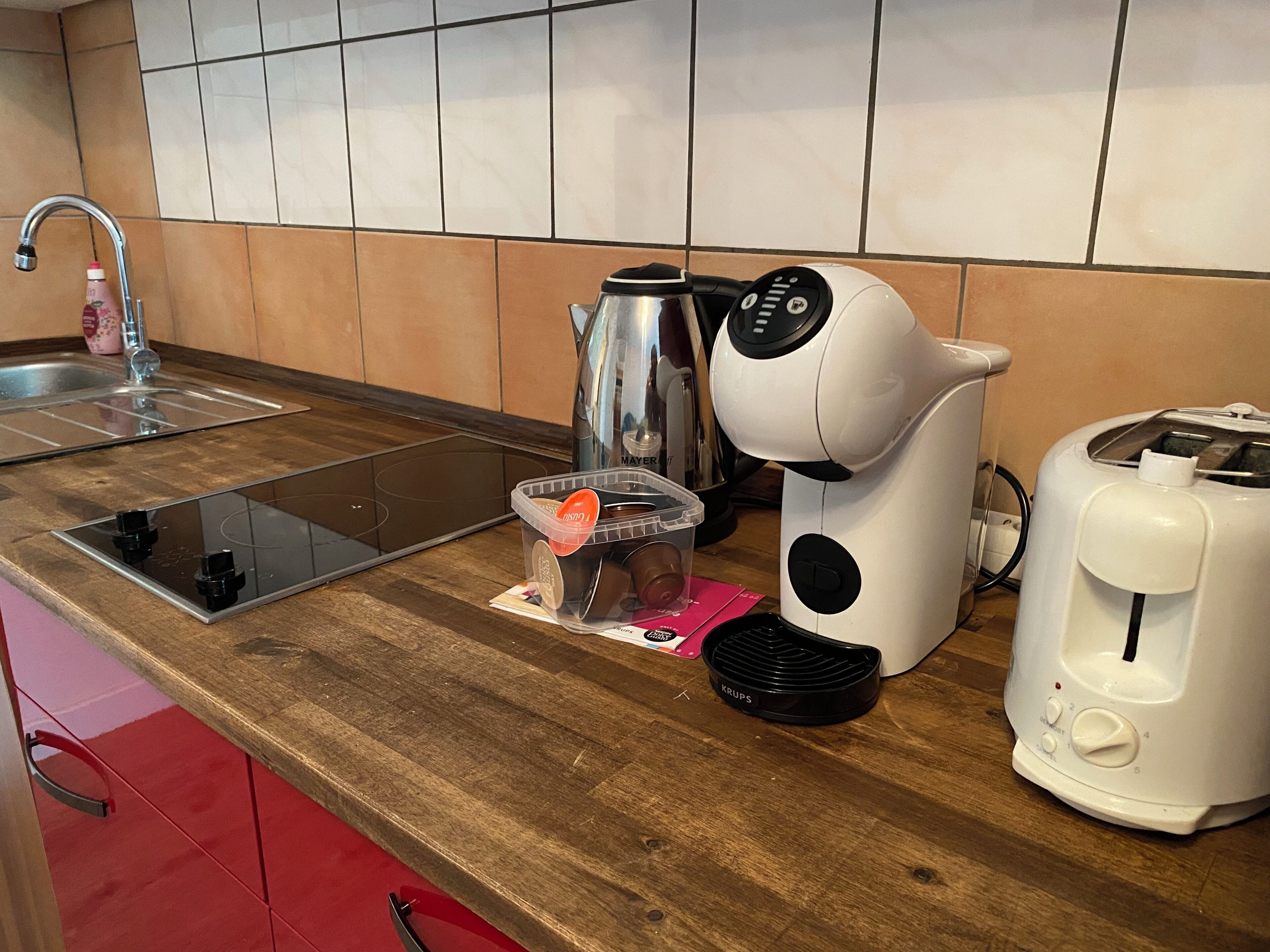 Eine Küche mit Spüle, Kaffeemaschine, Wasserkocher und Toaster auf einer Holzausziehtafel.
