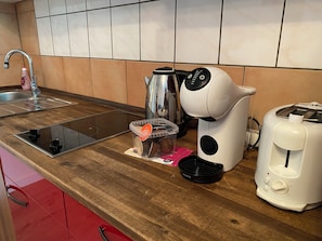A kitchen with a sink, a coffee maker, a kettle, and a toaster on a wooden countertop. - Cosy apartment in Reimsbach perfect for your stay (Beckingen)
