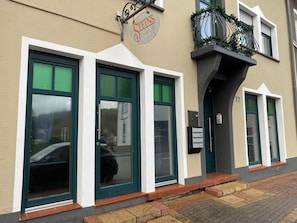 A building with large windows, a sign above the entrance, and a small balcony with greenery. - Cosy apartment in Reimsbach perfect for your stay (Beckingen)