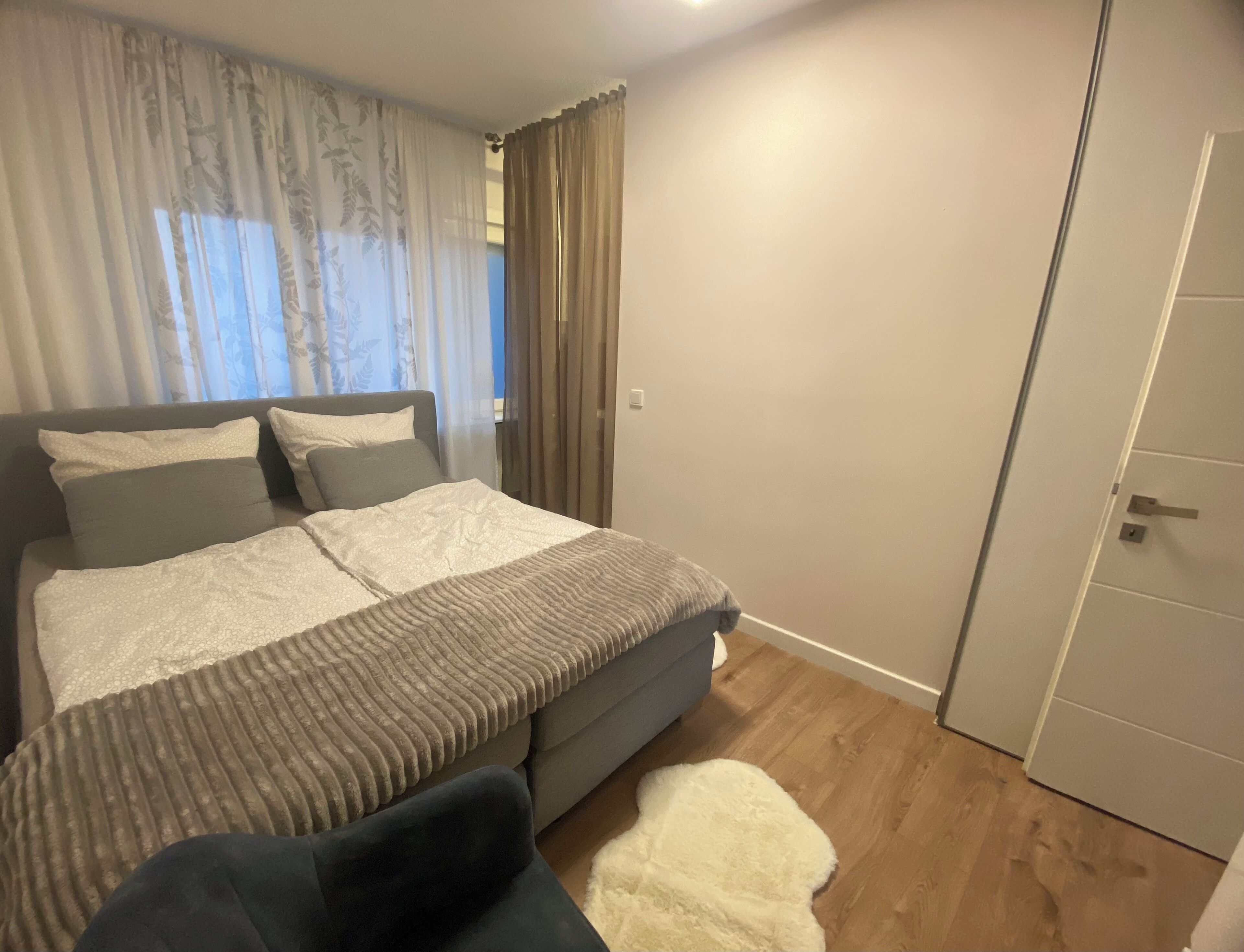 Ein Schlafzimmer mit einem Bett, einem Sessel, einem weißen Teppich und einer Tür.