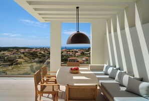 A terrace with a dining table, chairs, and a sofa with cushions. A large pendant light hangs above the table. - Casa Blanca Villa, Pool, SeaViews & Wine Cellar (Zakynthos)
