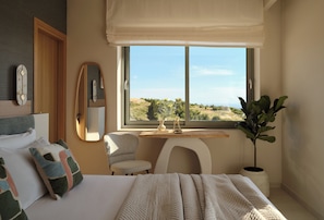 Une chambre avec un lit, un bureau, une chaise, une grande fenêtre et une plante en pot.