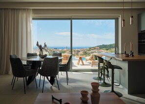 A modern dining area with a view of the sea, a pool, and a terrace.