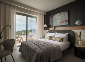 A hotel room with a large bed, a view of the outdoors, a dining area, and a modern design. - Casa Blanca Villa, Pool, SeaViews & Wine Cellar (Zakynthos)