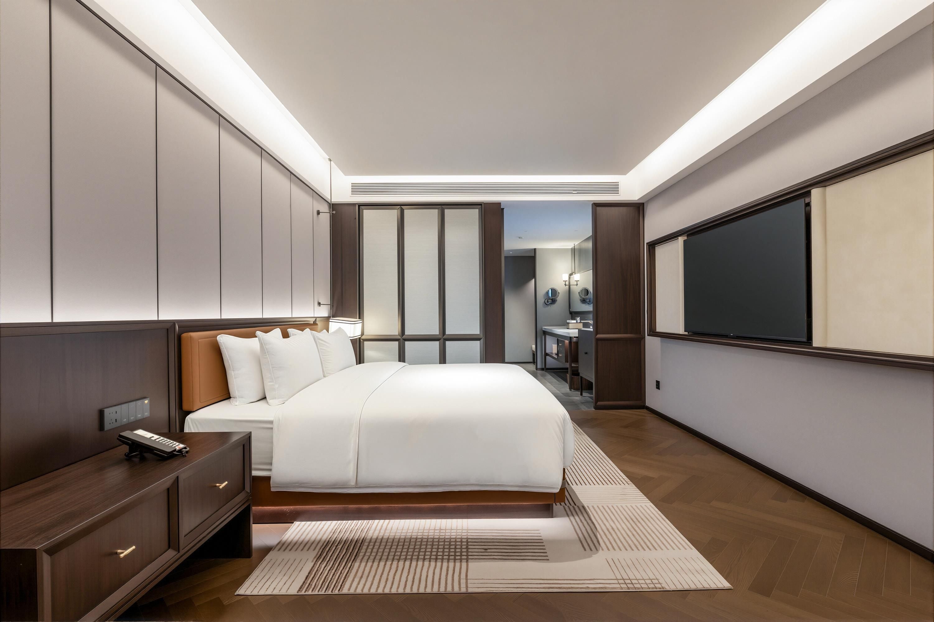 Una habitación de hotel moderna con una cama grande, mesitas de noche, un escritorio y un espejo amplio.
