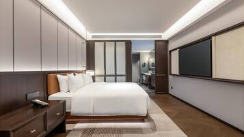 Una habitación de hotel moderna con una cama grande, mesitas de noche, un escritorio y un espejo amplio.