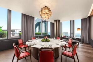 Uma sala de jantar moderna com uma mesa redonda, cadeiras vermelhas e vista para a cidade.