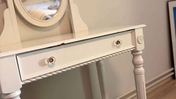 A white vanity with a mirror, two drawers, and a small stool.