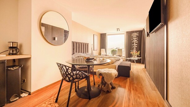 Een moderne hotelkamer met een zithoek, een ronde tafel en een bank.