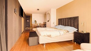 Een moderne slaapkamer met een groot bed, nachtkastjes, een flatscreen televisie en een spiegel aan de muur.