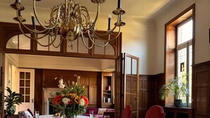 A dining room with a chandelier, wooden paneling, and a table set for a meal.