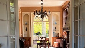 A dining area with a chandelier, a table, chairs, and a view of the outdoors.