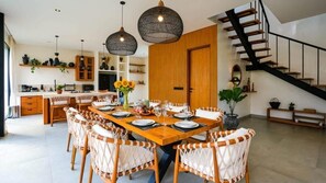 Eine moderne Küche mit Holzausstattung, ein Essbereich mit Korbstühlen und eine Treppe.