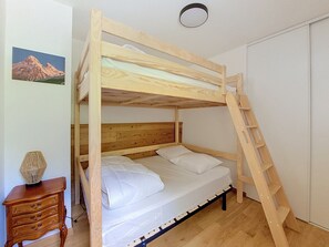 Ein Stockbett mit Holzleiter, ein Nachttisch und ein an der Wand hängendes Bild.