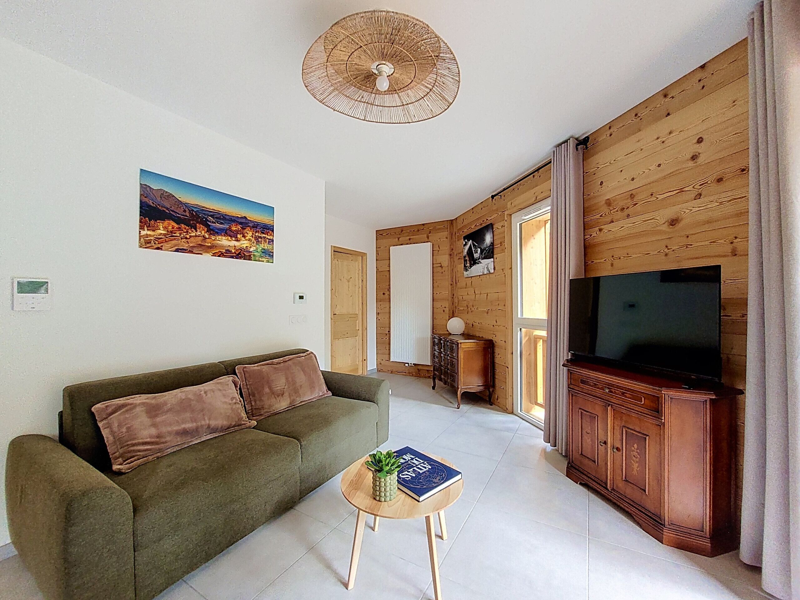 Una sala de estar con un sofá, una mesita con un libro y una planta, un televisor y paneles de madera en las paredes.