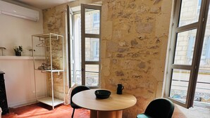Ein Zimmer mit rundem Tisch, zwei Stühlen, einem Schuhregal und Blick durch ein Fenster.