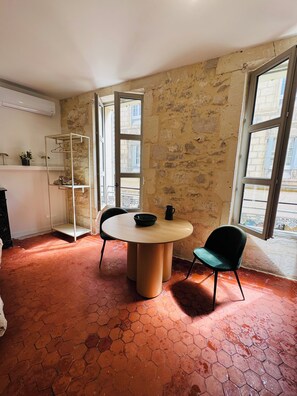 A room with a round table, two chairs, a shoe rack, and a view through a window. - Charming, renovated apartment in the heart of Arles (Arles)