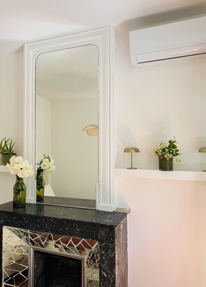 A bathroom with a large mirror, a marble countertop, a wall-mounted air conditioner, and two potted plants on a shelf. - Charming, renovated apartment in the heart of Arles (Arles)