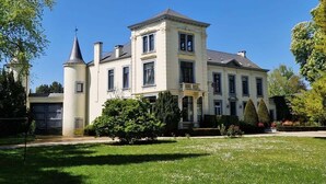 Un grand bâtiment à deux étages, doté d’une façade symétrique, d’une entrée centrale et d’une tour située sur le côté gauche.