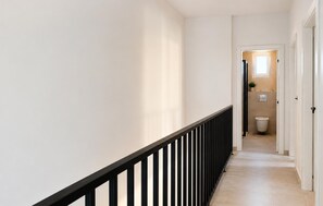 A narrow hallway with a black railing, leading to a bathroom with a toilet and a small window. - Nice home in Privlaka (Privlaka)