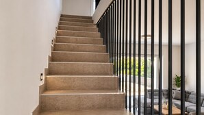Un escalier au design moderne, menant à un espace de vie comprenant un canapé et une table basse.