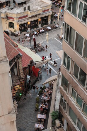 An outdoor café area with tables and chairs, surrounded by buildings with large windows. - Oddity Seafront Penthouse Apartments (Thessaloniki)