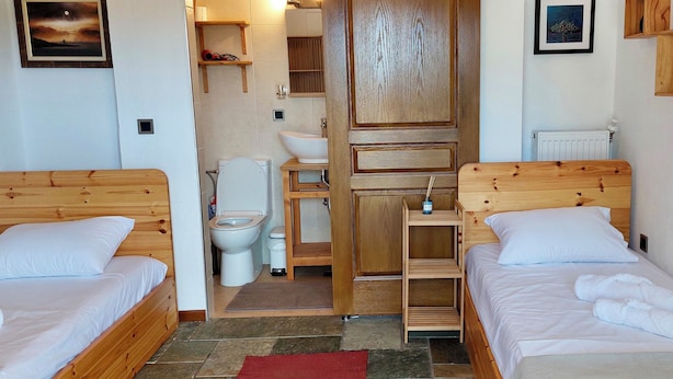 A bedroom with two wooden beds, a wooden wardrobe, a white toilet, and a sink. - Oddity Seafront Penthouse Apartments (Thessaloniki)