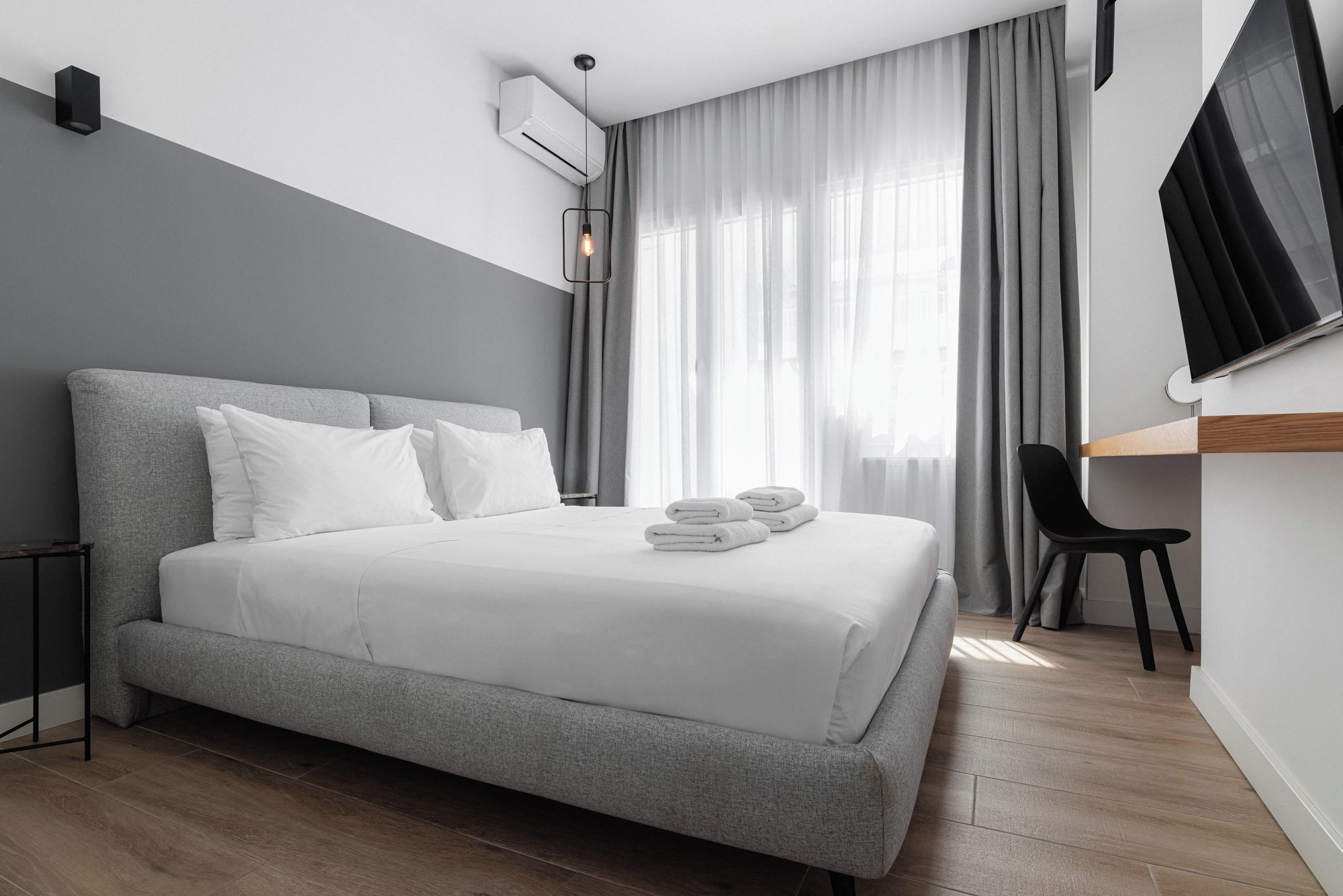 Une chambre d’hôtel moderne avec un grand lit, un bureau et une chaise.