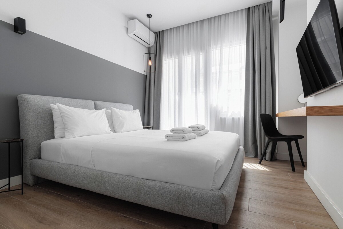 A modern hotel room with a large bed, a desk, and a chair.
