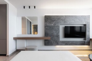 Un salon moderne avec un téléviseur à écran plat fixé sur un mur en marbre, un banc en bois et un pouf rond.