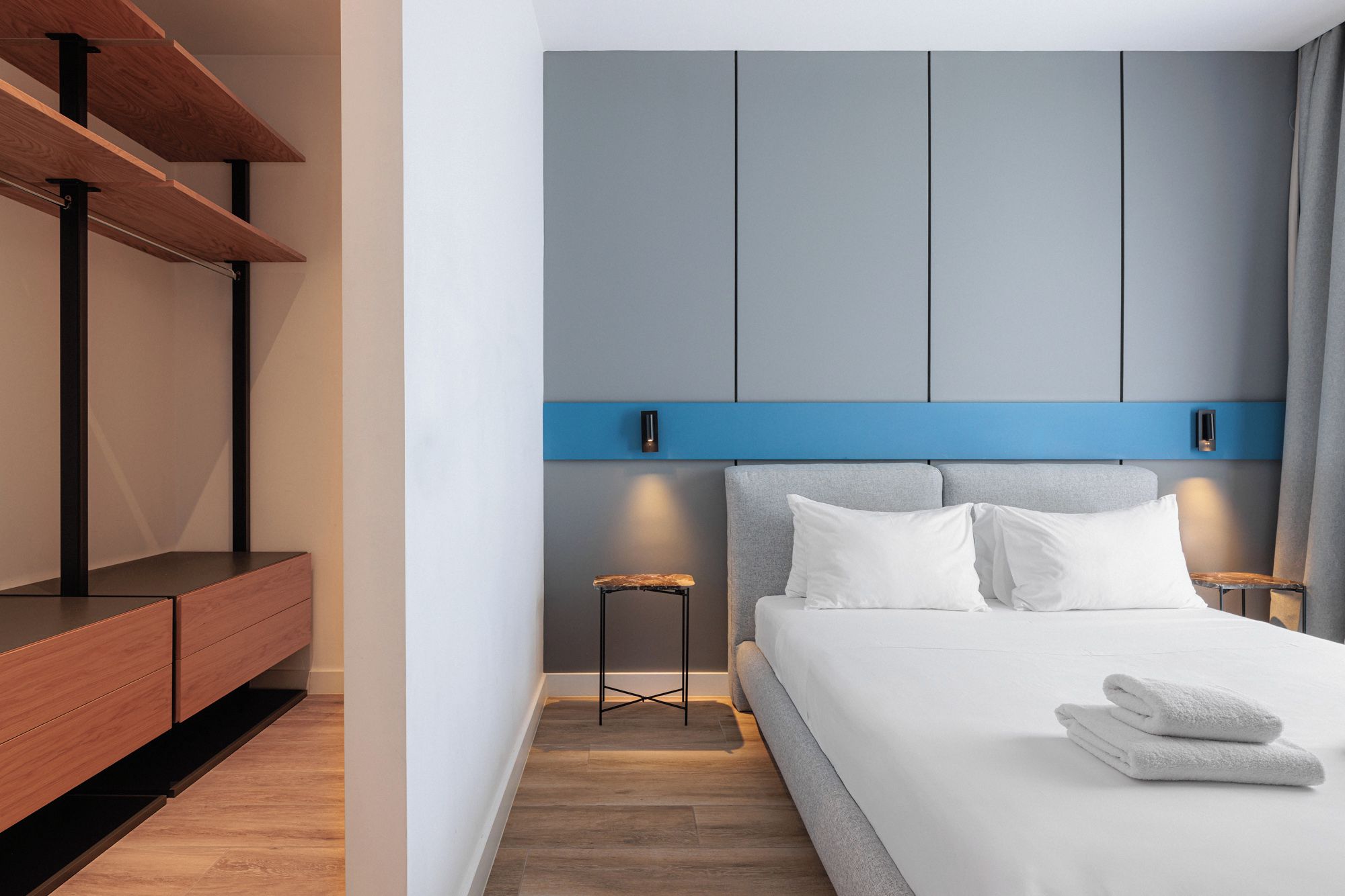 Une chambre à coucher moderne avec un lit, des tables de chevet et un banc intégré.