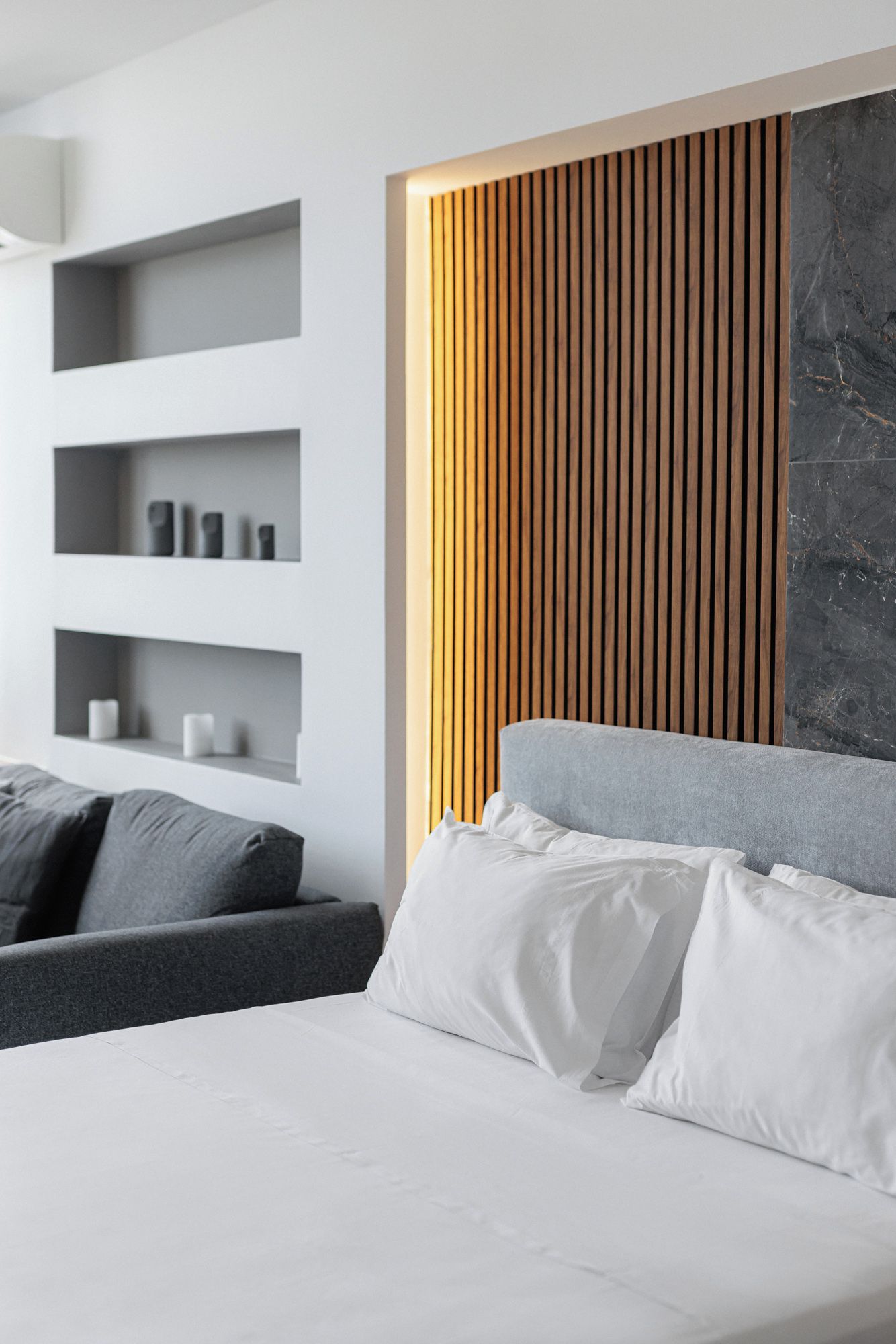 Une chambre à coucher moderne avec un lit, un canapé gris et des étagères intégrées.