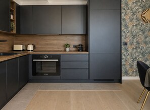 Une cuisine moderne avec des meubles de couleur sombre, un four Bosch, un grille-pain et une bouilloire posés sur le plan de travail.