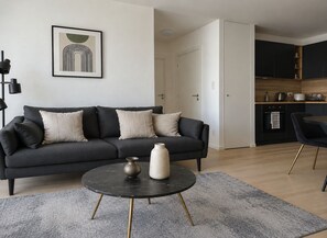 Ein modernes Wohnzimmer mit einem dunkelgrauen Sofa, einem runden Couchtisch und einer minimalistischen Einrichtung.