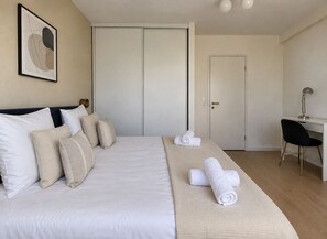 Ein Hotelzimmer mit Bett, Schreibtisch, Stuhl und einer Tür.