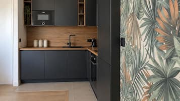 Een moderne keuken met donkere kastjes, een houten aanrechtblad en een ingebouwde magnetron.